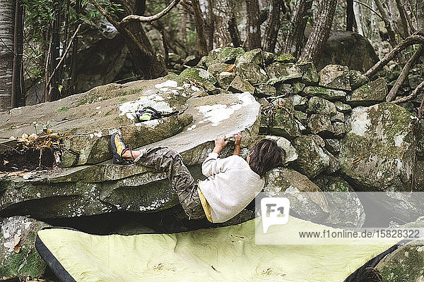 Ein junges Kind klettert auf einen Felsen im Wald