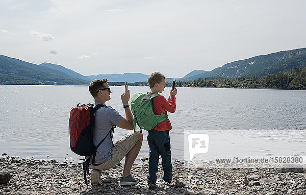 Vater und Sohn fotografieren mit ihren Handys die Berge