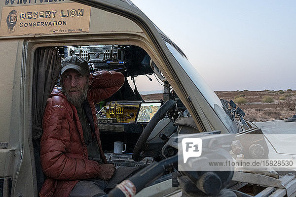 Forscher steht in seinem Fahrzeug in der namibischen Wüste