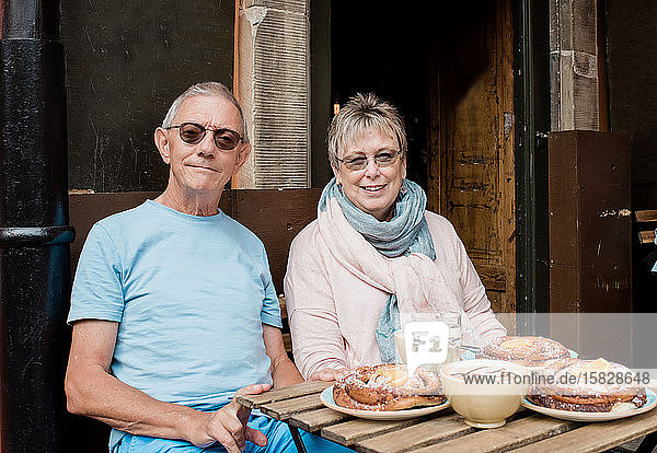 portrait of older couple sat at a cafe eating whilst travelling