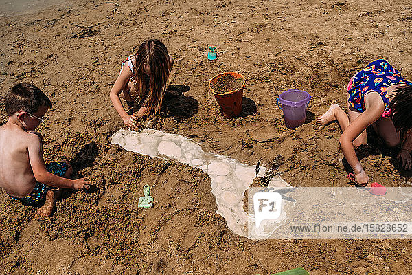 children digging in sand on a sunny day at the beach