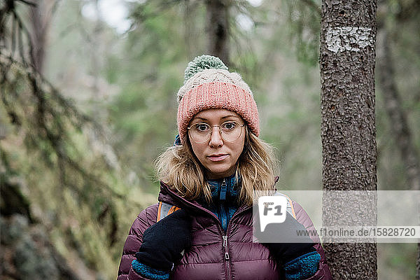 Porträt einer Frau  die im Winter allein durch einen Wald in Schweden wandert