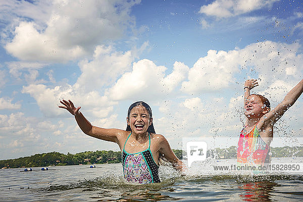 Two Young Girls in Swimsuits Splashing in a Lake