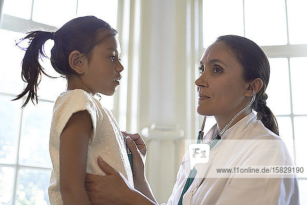 Allgemeinmedizinerin mit Stethoskop bei der Untersuchung eines jungen Mädchens