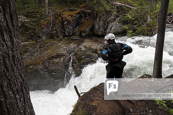 A female kayaker scouts a waterfall before sending it on the Cheakamus