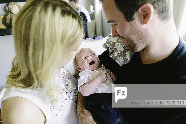 Ein neugeborener Junge lächelt  während ihm seine Eltern helfen