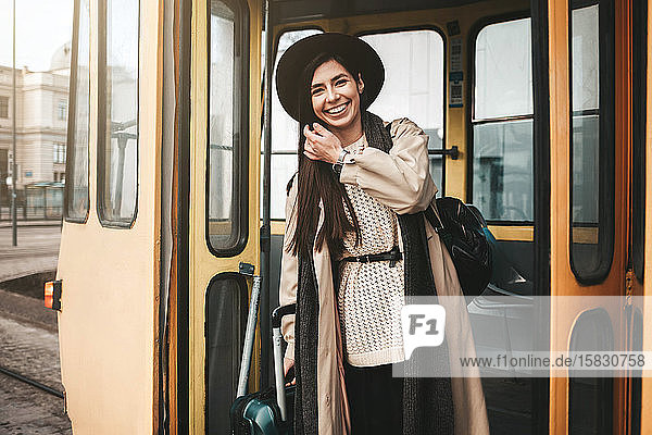 Schöne stilvolle Reisende mit Koffer steigt aus der Straßenbahn