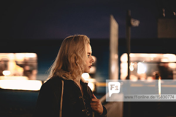Junge Frau  die am U-Bahnhof steht und nachts mit dem Zug fährt
