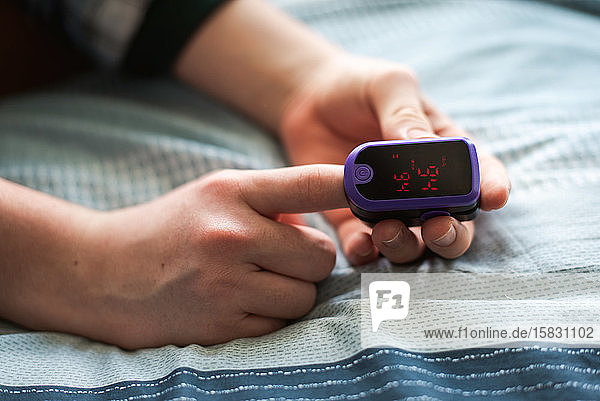 Close up of a person putting a pulse oximeter on their finger.