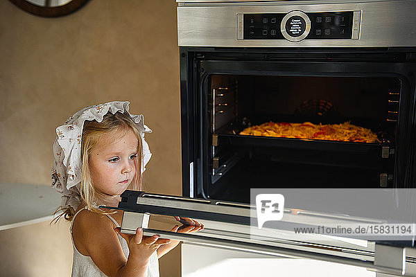 Kleines Mädchen kocht Pizza in der Küche