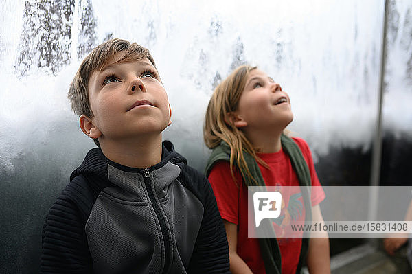 Two children looking up with wonder at waves and water