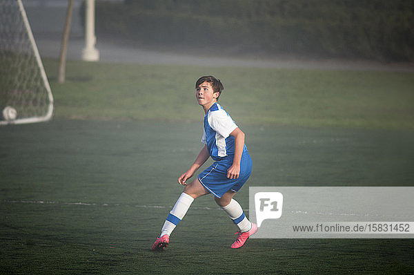 Teenager-Fussballer bereit zur Verteidigung auf nebligem Feld