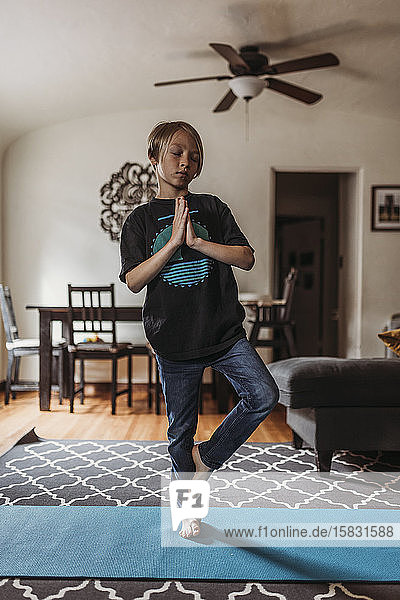 Schulpflichtiger Junge macht während der Isolation Yoga im Wohnzimmer