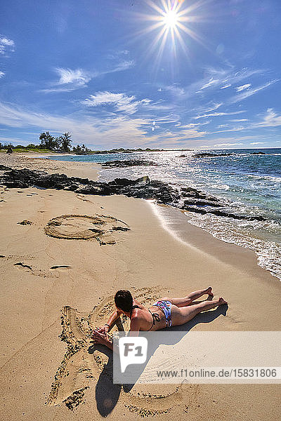 Eine Frau bastelt Figuren im Sand am Makalawena-Strand  Hawaii