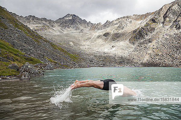 Mann taucht im Upper Reed Lake  Talkeetna-Gebirge  Alaska  zum Schwimmen ein
