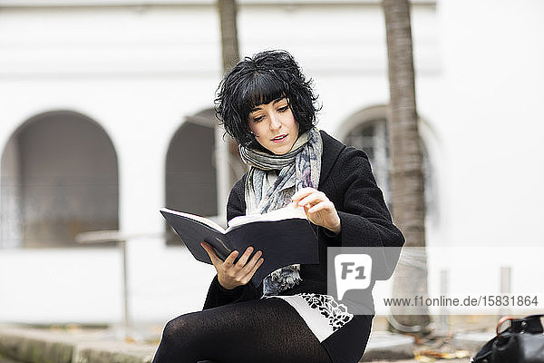 junge Frau  die draußen in einem Buch liest