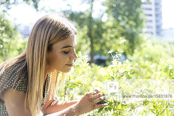 Junge blonde Frau redaktionell geschlossen duftende Blumen in einem Park