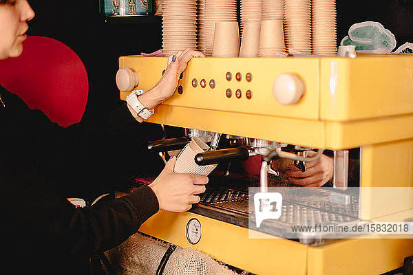 Weibliche Baristain bereitet Tee mit der Kaffeemaschine zu