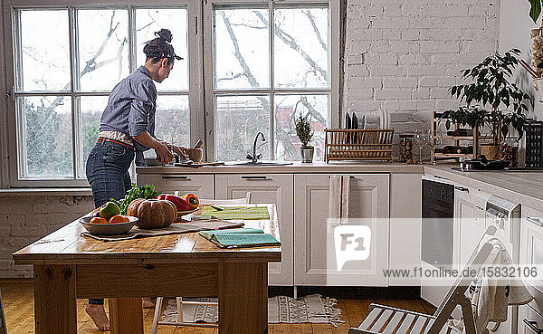 Junge und schöne Hausfrau  die in einer weißen Küche kocht
