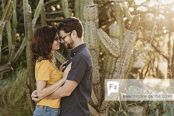 Husband and wife hugging each other in sunny cactus garden