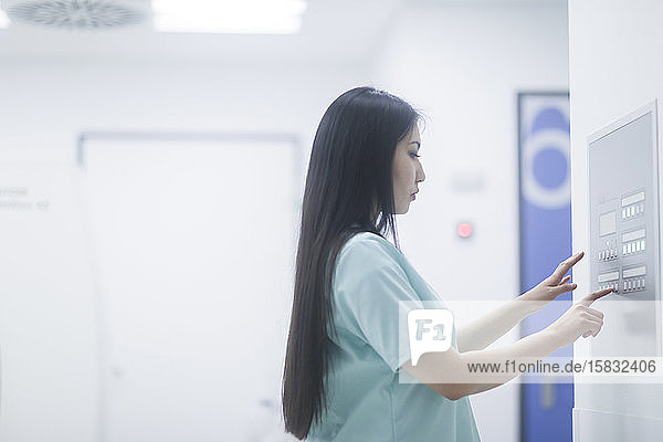 asiatische Krankenschwester bei der Kontrolle einer Schalttafel