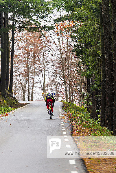 gesunder Mann  der an einem nebligen Tag auf einer Bergstraße Fahrrad fährt