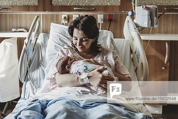 Mittelansicht der Mutter im Krankenhausbett mit Blick auf den neugeborenen Sohn