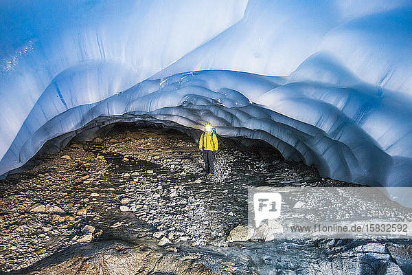 Forscher steht unter einem Gletscher in einer Höhle.