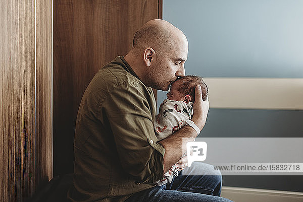 Side view of happy father kissing newborn boy in hospital
