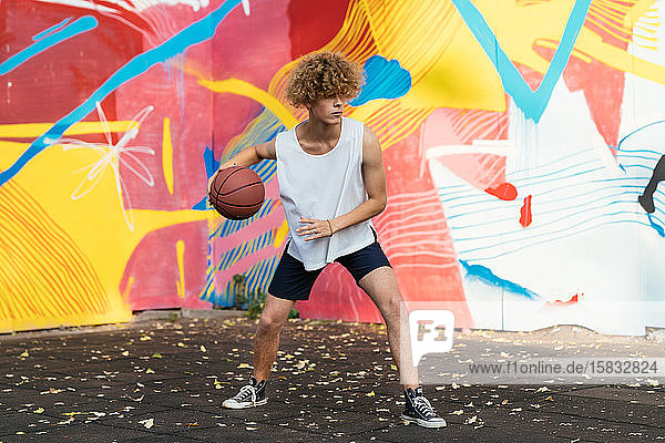 Junge Männer mit kurvenreichem Haar spielen Basketball draußen auf einem Platz