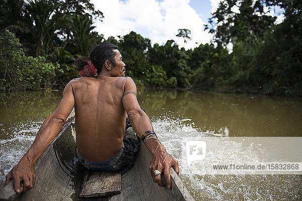 Ein Mann des Mentawai-Stammes sitzt im Kanu und fährt auf dem Fluss