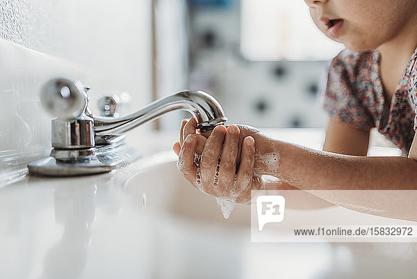 Nahaufnahme eines Kleinkindes beim Händewaschen mit Seife im Waschbecken