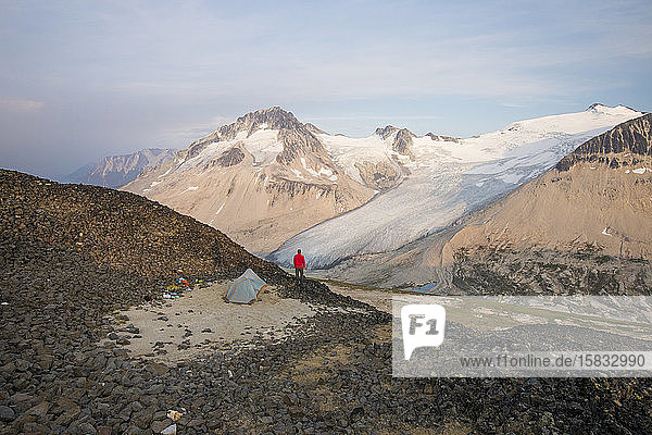 Wanderer steht neben dem Zelt auf dem Berggipfel.