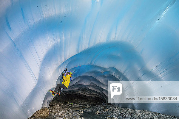 Seitenansicht des Bergsteigereiskletterns in einer Gletschergrotte.
