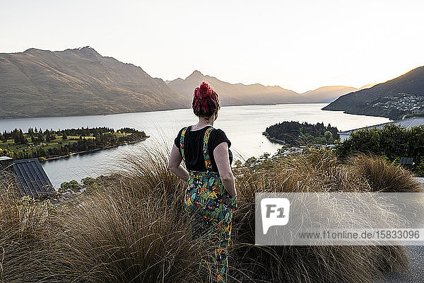 Frau mit Blick auf Queenstown und See  bei Sonnenuntergang in Neuseeland