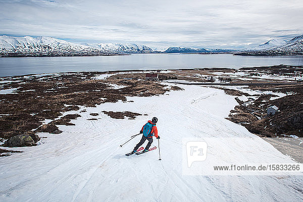 Frau fährt in Island auf Skiern Richtung Meer