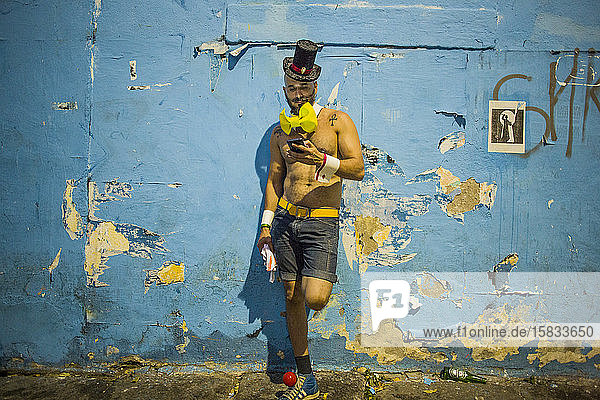 Mann in Kostüm genießt den Karneval von Rio de Janeiro per Smartphone