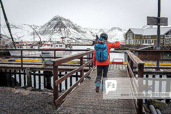 A woman walking with skis onto a dock in Iceland