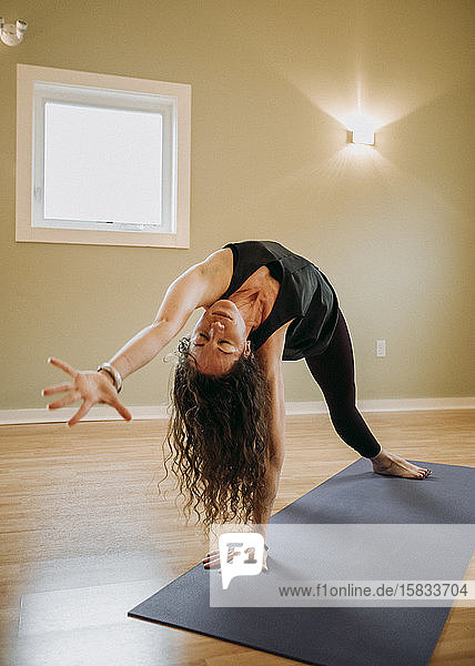 Weibliche Person mit geschlossenen eeditorischen Konzentraten beim Üben von Yoga in geschlossenen Räumen