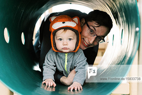 Kleiner Junge mit Fuchshut der mit seinem Papa auf dem Spielplatz spielt.