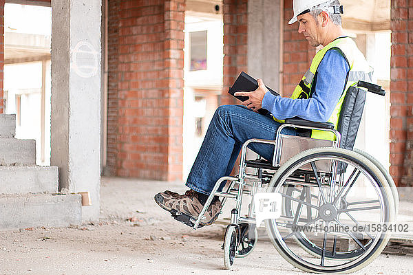 Rollstuhlbautechniker  der eine Baustelle beaufsichtigt
