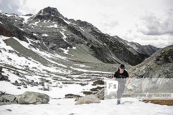 A women hikes up a snow field on a summer day in the mountains for British Columbia.