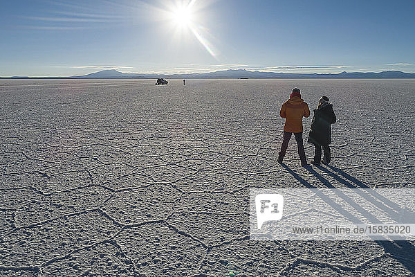 people and their elongated shadows while photographing the salar
