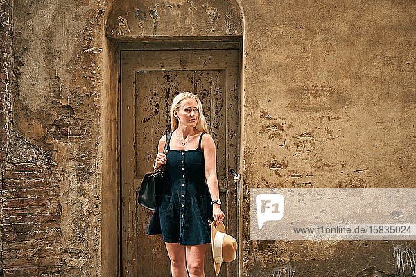 Attraktive Frau steht an gepunkteter Tür eines alten Hauses