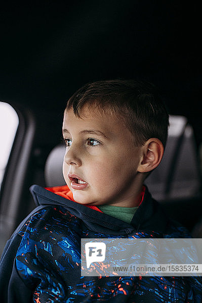 Boy waiting for friends inside car and looking out window in Texas