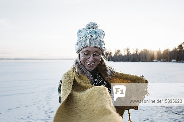Frau lächelt beim Spaziergang auf einem zugefrorenen See im Winter in Schweden