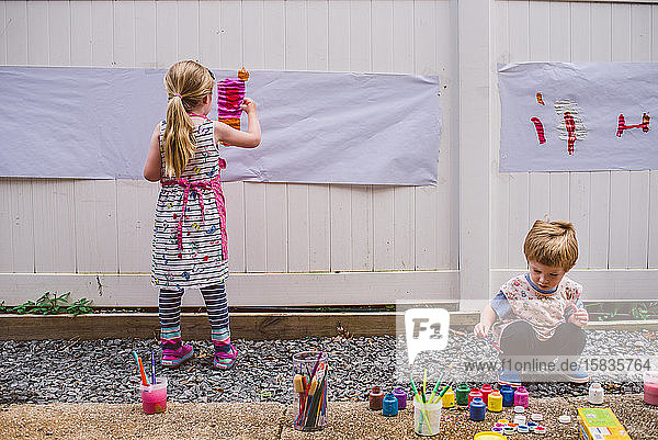 Zwei Kinder malen draußen.