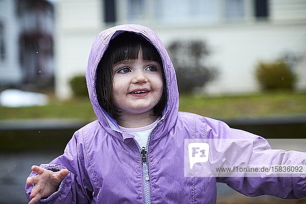 Das Porträt eines kleinen Mädchens im Freien an einem regnerischen Tag.