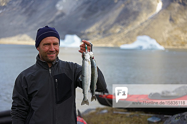 Mann hält frischen Seesaibling in Grönland