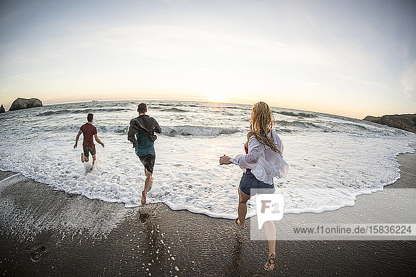 Gruppe von Teenagern  die sich bei Sonnenuntergang am Strand vergnügen